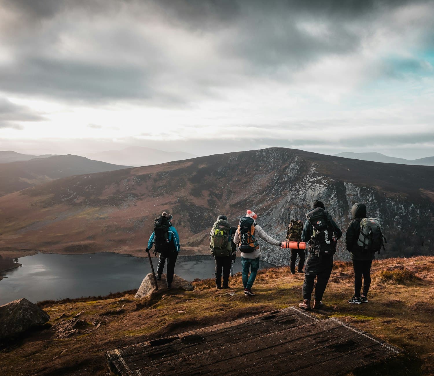 A small group of travellers standing together on a ridge above a loch