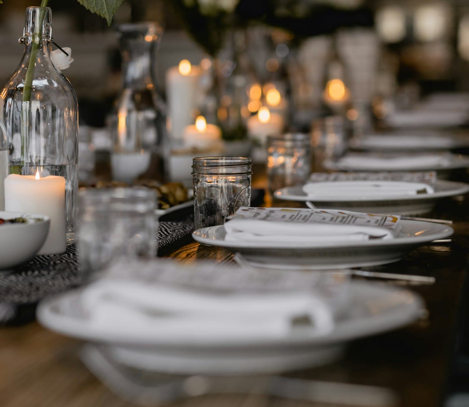 A long banquet table set with candles and glassware