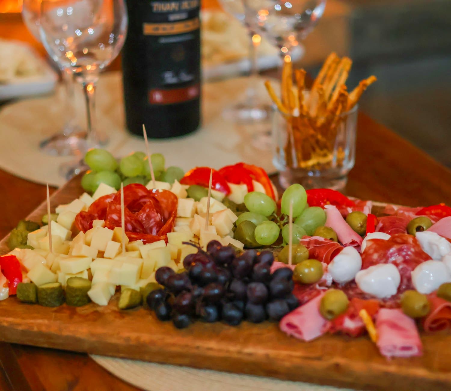 A rustic board of local cured meats, cheese and grapes with wine