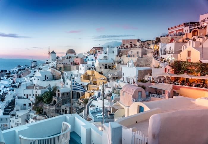 Whitewashed village lights glowing at dusk above the caldera